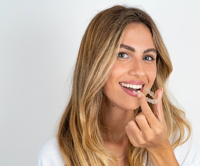 Woman in white shirt about to put in clear aligner