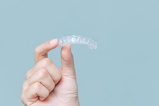 Hand holding a clear aligner 