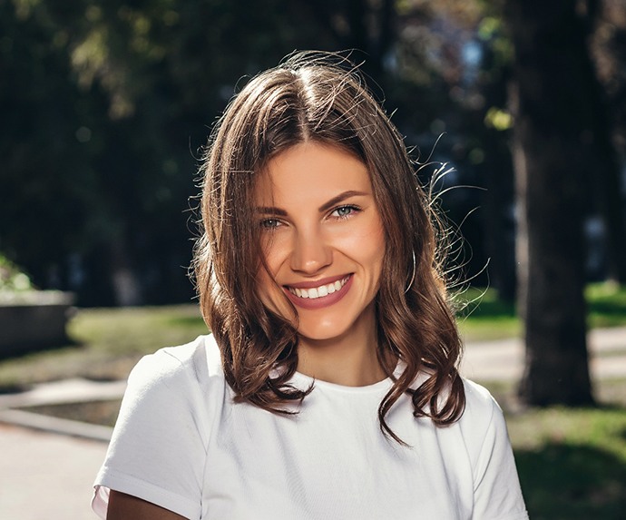 Smiling woman in white shirt walking through a neighborhood