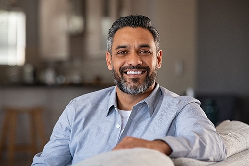 Bearded man sitting on couch and smiling