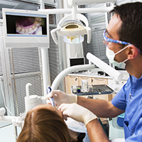 Dentist and patient look at images of teeth on monitor
