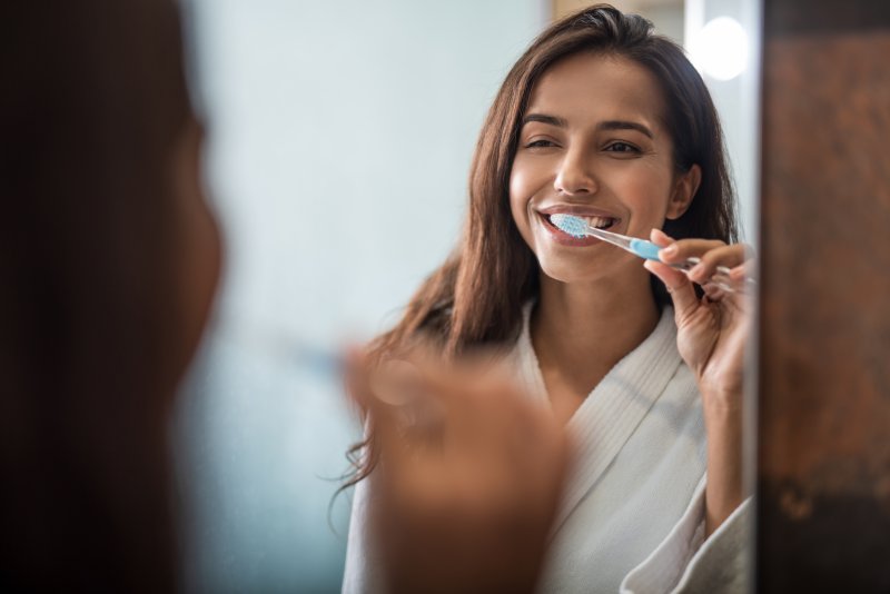 Woman smiling while brushing her teeth