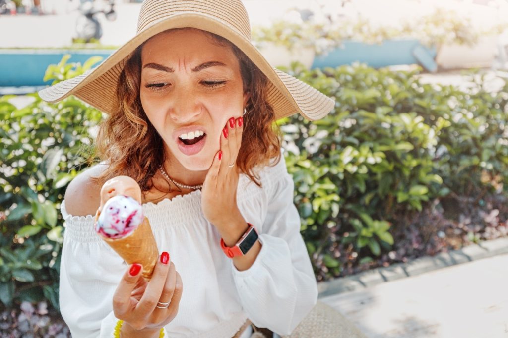 Woman experiencing tooth sensitivity while on vacation