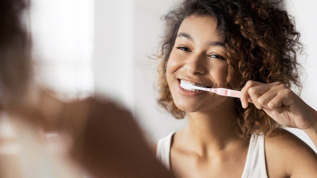 Closeup of woman smiling while brushing her teeth