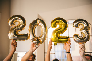 People holding up balloons that say “2023”