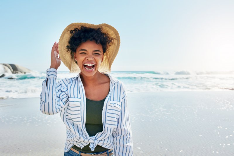 a woman with healthy teeth smiling at the beach