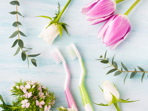Two toothbrushes lying among flowers and various plants